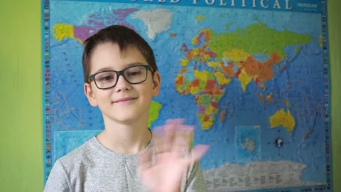 A boy with glasses waves his hand standing against the background of a political Stock Footage 165460704