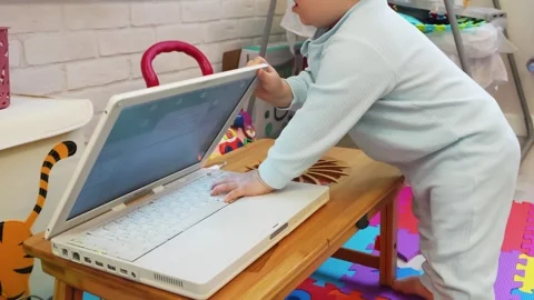 A boy gleefully plays with a laptop Stock Footage 266751604
