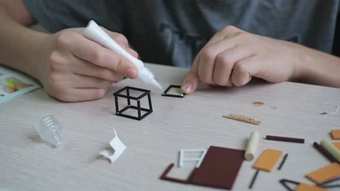 The boy glues a model on the table. close-up of the hands gluing the parts Stock Footage 169531899