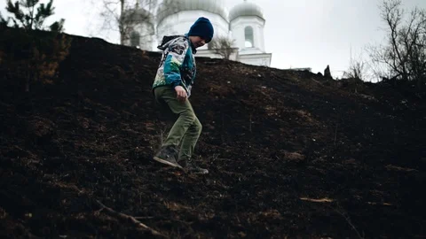 The boy goes down the slope with burnt grass. Beautiful dynamic frames Stock Footage 128016603