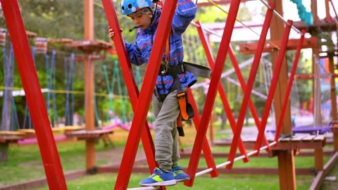 A boy goes through an obstacle course, a panda park on hanging ropes Stock Footage 198826972