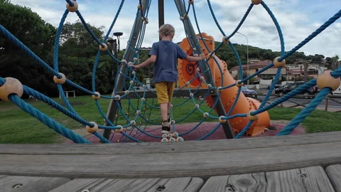 A boy goes through an obstacle course on a rope course at a playground	 Stock Footage 311925685