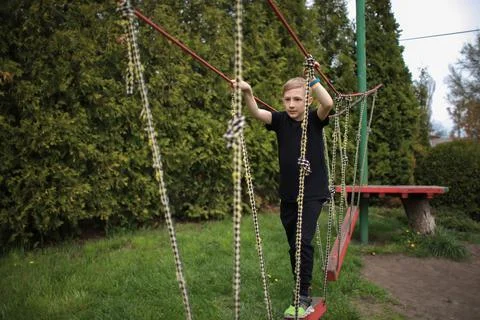 The boy goes through an obstacle course, goes in for active sports, walks on  Stock Photos