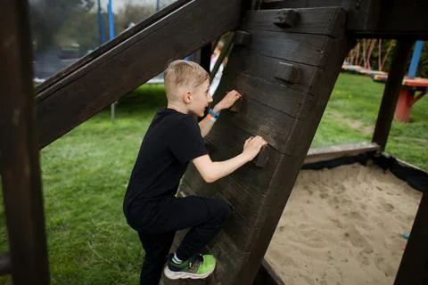 The boy goes through an obstacle course, goes in for active sports, climbs a  Stock Photos