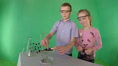 Boy in goggles pours reagent. 库存影片 60606234