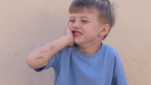 Boy in a good mood smiles with scratched hand and wound on his elbow outdoors Stock Footage 321817136