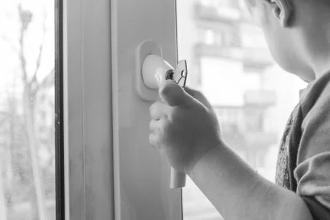 The boy grasps the handle of the window. A small child holding the handle of  Stock Photos