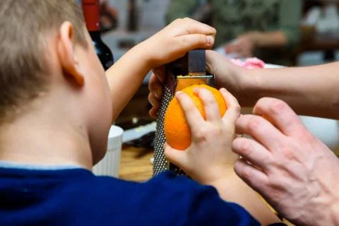 Boy grates orange at cooking workshop Stock Photos