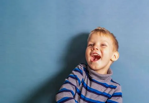 A boy in a gray striped jacket laughs when he sees something in front of him, Stock Photos