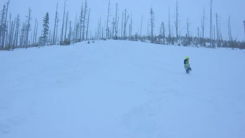 Boy in a Green Jacket Hiking Through Deep Snow Stock Footage 102928645