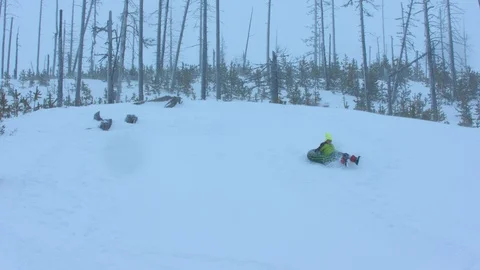 Boy in a Green Jacket Sledding Down a Hill in Slow Motion Stock Footage 102932829