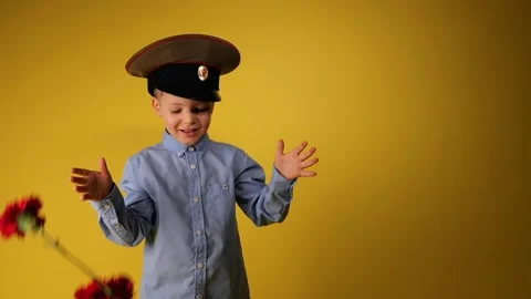 The boy in green military cap throws red flowers carnation in 9 may or 23 februa Stock Footage 147647998
