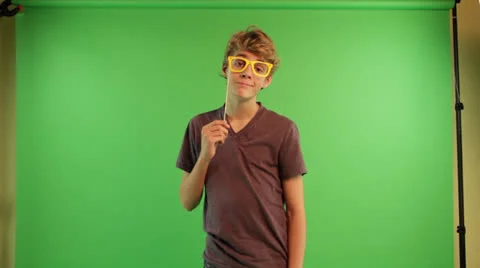A boy at the green screen background is holding nose glass stick mask Stock Footage 22902457