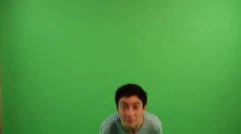 A boy at the green screen background is jumping twice with his arms wide open Stock Footage 22900423