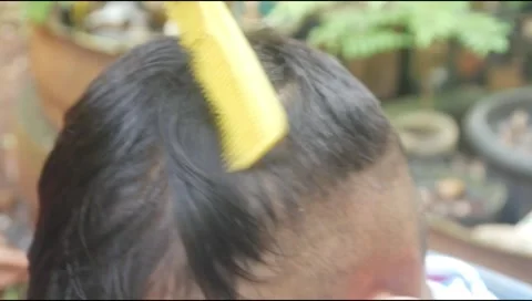 Boy hair being shaved using scissors outdoors Stock Footage 313734623