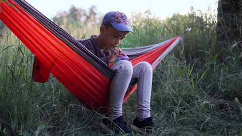 A boy in a hammock plays pop it. Boy in nature. White boy on a hike, resting in Stock Footage 242842090