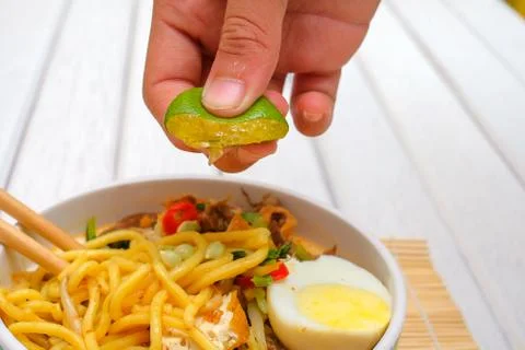 Boy hand squeezing lime on Malay Mee Rebus in the bowl  with chopsticks on wh Stock Photos