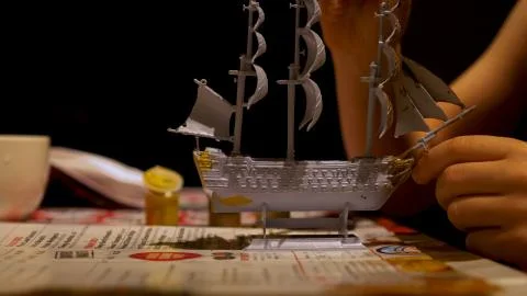 Boy hands assembling plastic model kit of ship at home. Hobby and leisure Photos