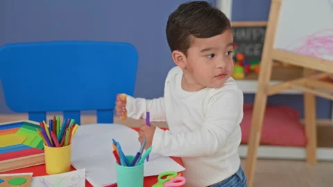 Boy hands holding purple marker over white paper at a child table with cups.. Stock Footage 339184761