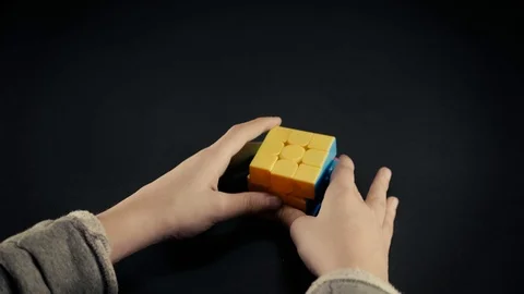 Boy hands solving Rubik's Cube 3x3x3 at dark background.Top view, 4k Stock Footage 125021939