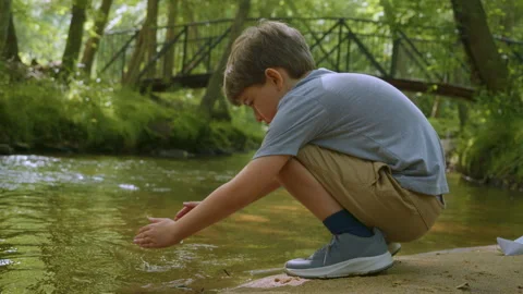 Boy Hands Touching River Flow. Child crouching by sparkling creek, touching.. Video stock 330800683