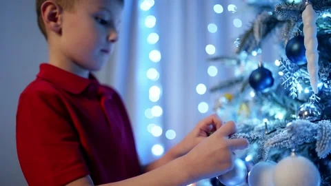 The boy hangs New Year's decorations on the Christmas tree. Stock Footage 258359123