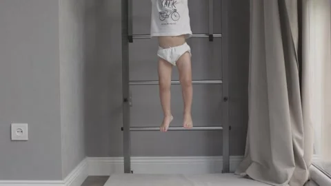 Boy hangs from pull-up bar on wall enjoying sports playful and energetic side of Stock Footage 280608278
