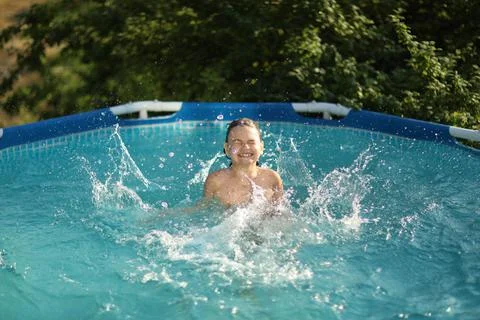 A boy happily splashes in the pool in the summer heat Stock Photos
