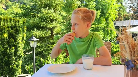 A boy has breakfast on an open terrace surrounded by greenery 스톡 동영상 317776018