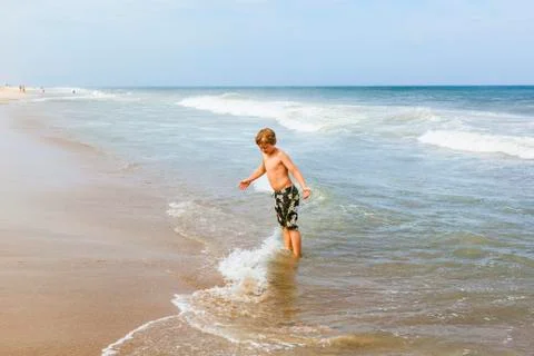 Boy has fun in the stormy beach Stock Photos