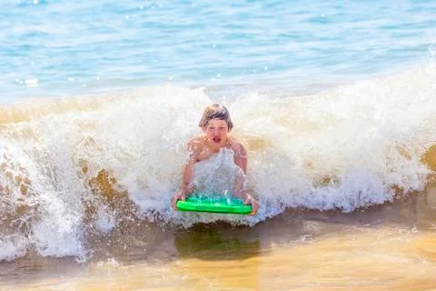 Boy has fun surfing in the waves Stock Photos