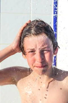 Boy has fun unter the pool shower Stock Photos