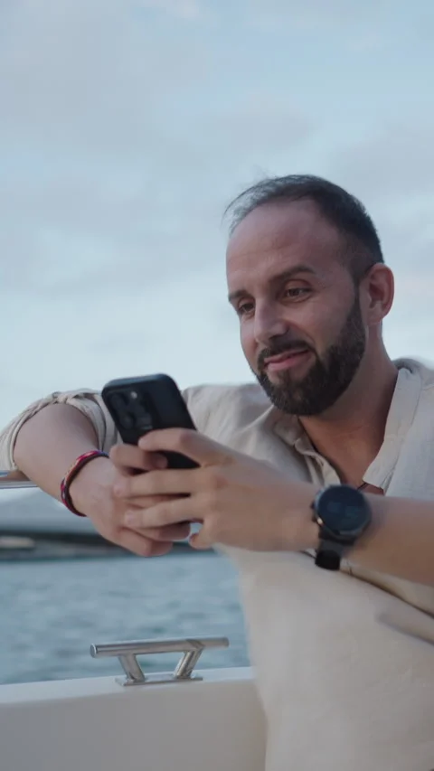 Boy has fun while looking at something on his cell phone in a boat Stock Footage 264923581