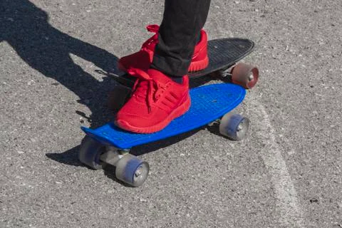 The boy has two feet on different skates. Skates of different colors. Stock Photos
