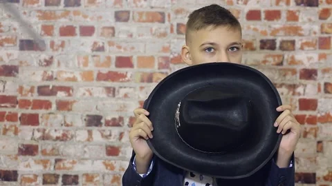 A boy with a hat in his hands covers his face Stock Footage 147920127