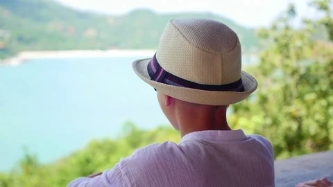 The boy in the hat looking into the distance the sea and mountains from the Vidéo 74762497