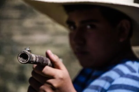 Boy with hat pointing with a rifle Stock Photos