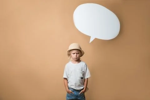 A boy in a hat stands on an orange background and shows emotions Stock Photos