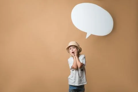A boy in a hat stands on an orange background and shows emotions Stock Photos