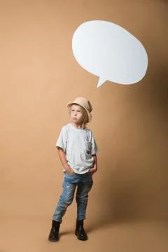 A boy in a hat stands on an orange background and shows emotions Stock Photos