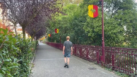 Boy in hat walks along river pensively and erratically, Ivrea, Italy, late Stock Footage 255831396