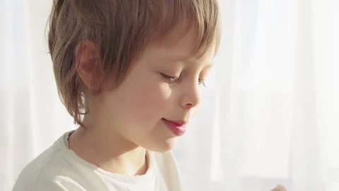 Boy have breakfast in modern kitchen. Boy eat cookie with milk. White Table in Stock Footage 103680116
