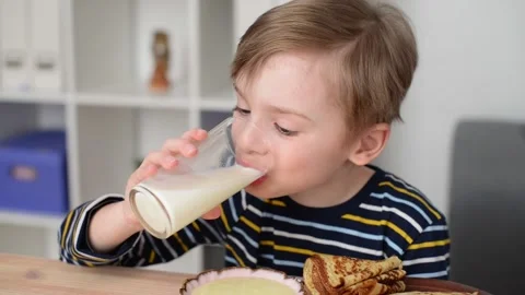 Boy having breakfast, drinking milk from a glass cup Stock Footage 194566108