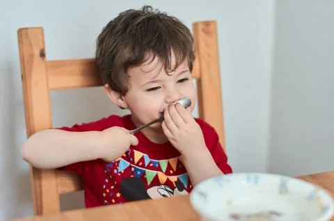 A boy is having fun at the breakfast table eating oatmeal Stock Photos