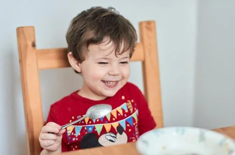 A boy is having fun at the breakfast table eating oatmeal Stock Photos