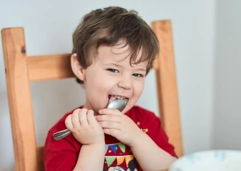 A boy is having fun at the breakfast table eating oatmeal Stock Photos