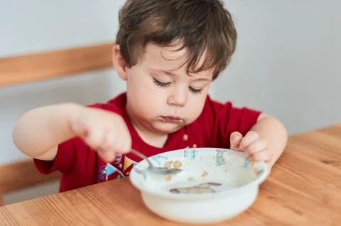 A boy is having fun at the breakfast table eating oatmeal Stock Photos