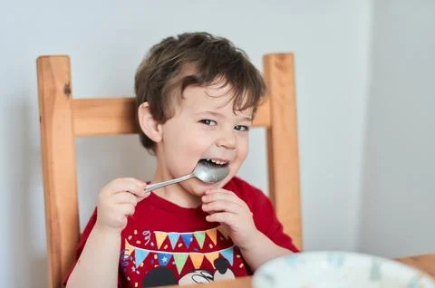 A boy is having fun at the breakfast table eating oatmeal Stock Photos