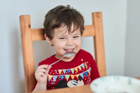 A boy is having fun at the breakfast table eating oatmeal Stock Photos