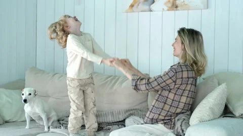 Boy having fun jumping on the sofa with his mother Stock Footage 296445692